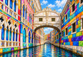 Bridge of Sighs in Harlequin Hues — the Bridge of Sighs over a narrow canal between colorful mosaic-tiled walls with Gothic windows