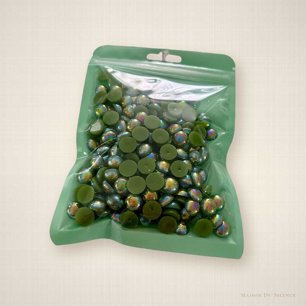 Peridot green half pearls styled on an ivory linen backdrop