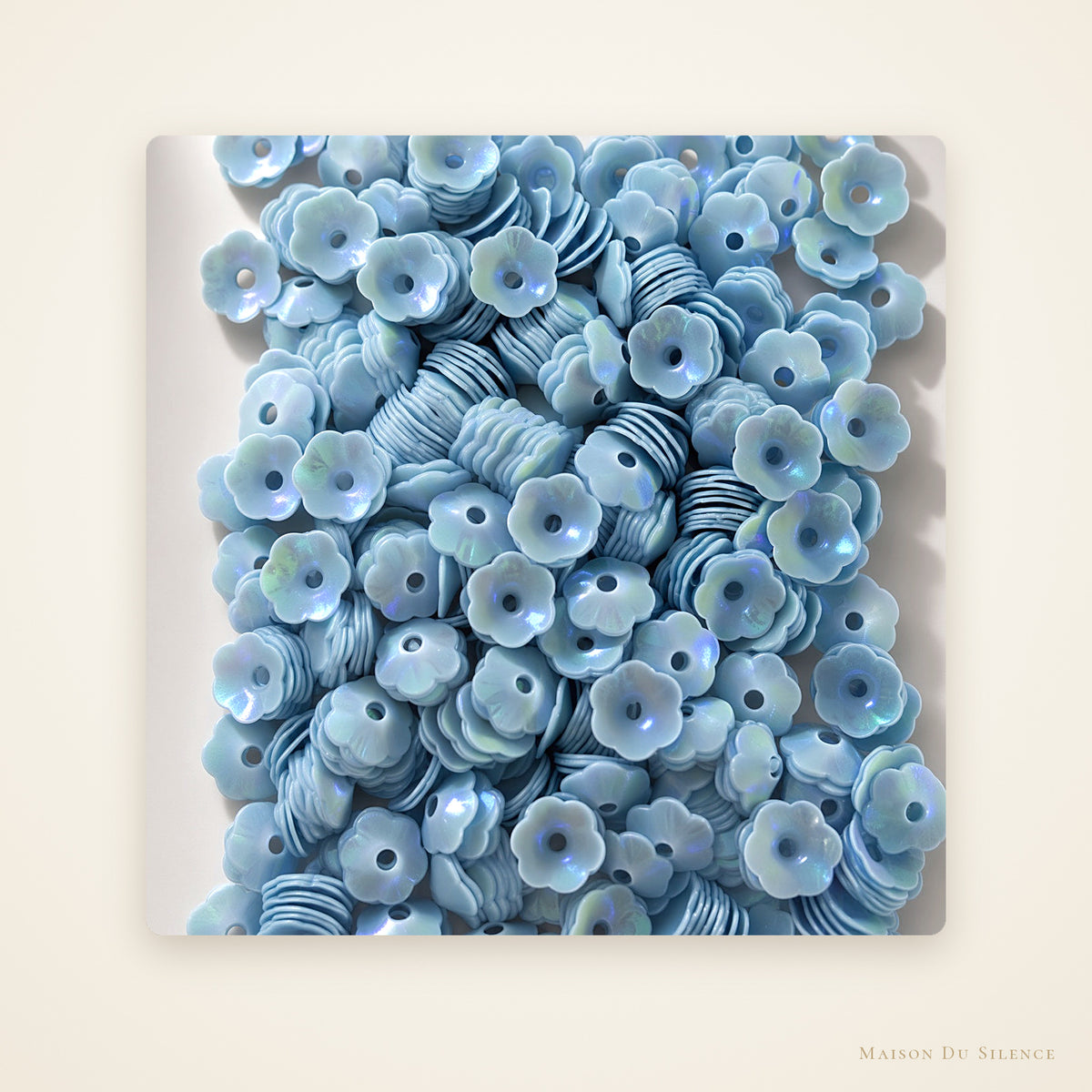 Blue iridescent 5 mm flower-shaped sequins on an ivory background