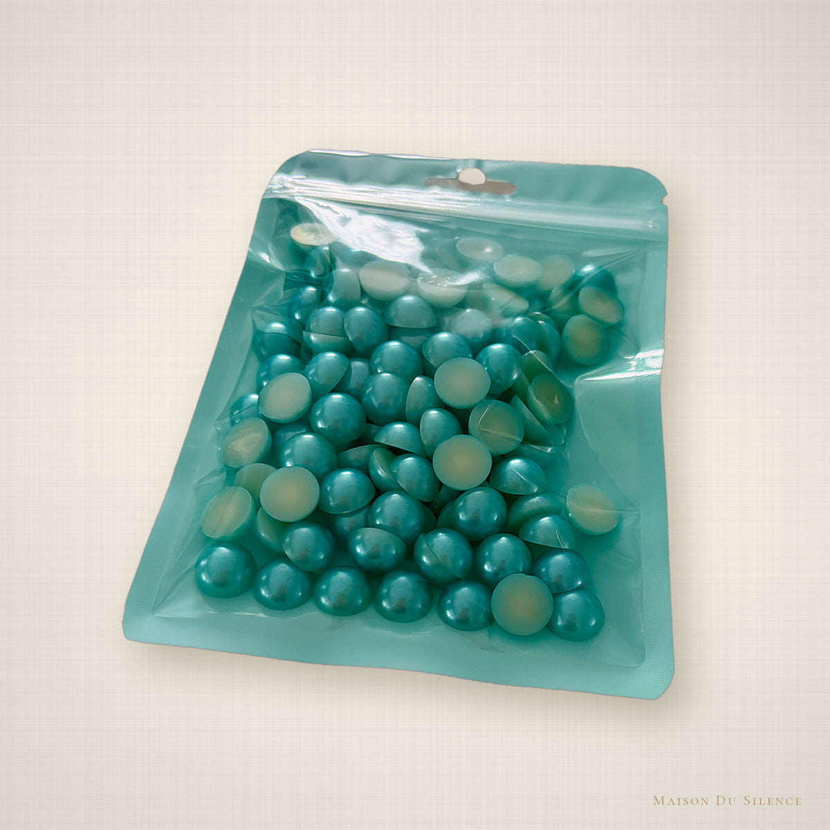 Aquamarine half pearls styled on an ivory linen backdrop